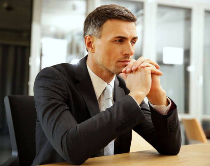 Professionally dressed man with hands clasped image used for workplace health and safety laws lawyer